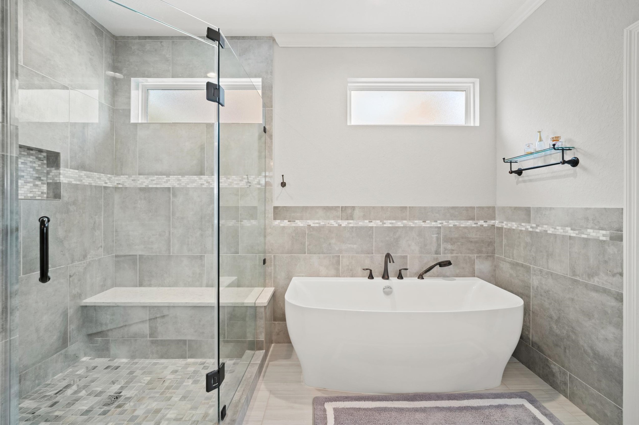 9507 Empress Crossing Drive Spring, TX 77379 - Photo 27 of 50 This bathroom features a modern design with a spacious glass-enclosed shower, a sleek freestanding bathtub, and elegant gray tile work. Natural light filters through a high window, enhancing the serene atmosphere.