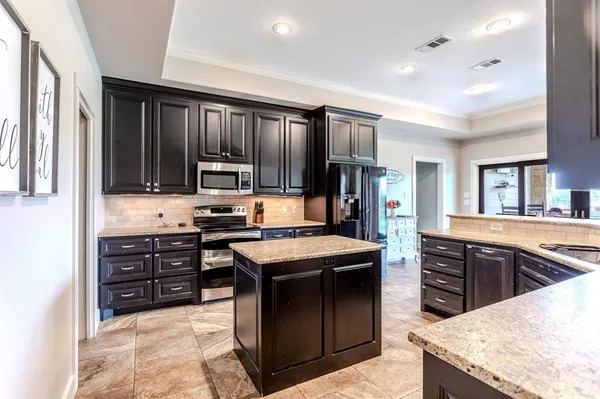 a kitchen with granite countertop a sink a stove and cabinets