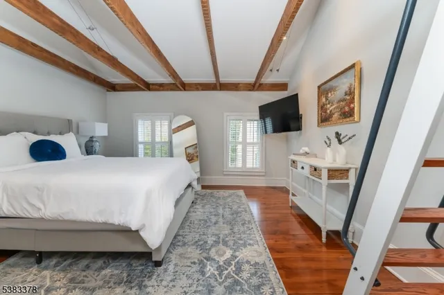 a bedroom with a bed a flat screen tv and a large window with the garden view