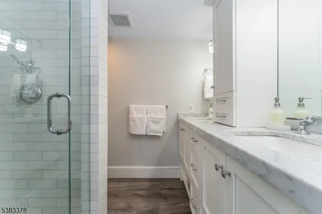 a bathroom with a double vanity sink a toilet and shower