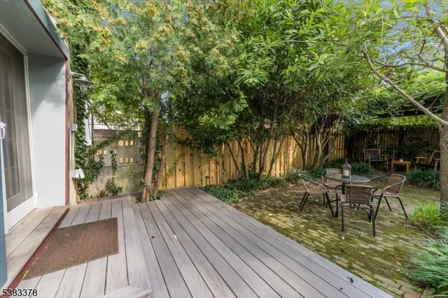 a view of patio with table and chairs and potted plants with wooden floor and fence