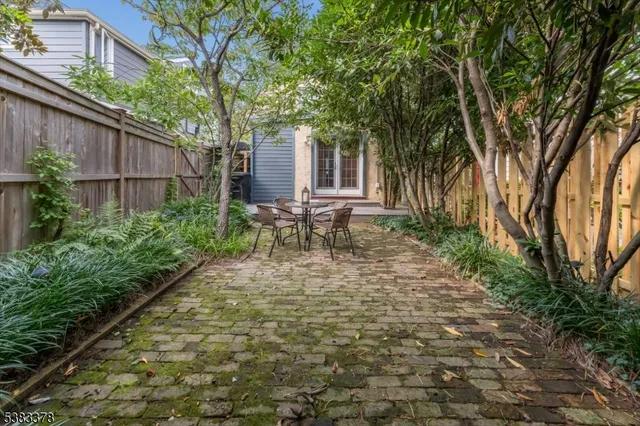 a view of a backyard with table and chairs and a barbeque with potted plants and large trees