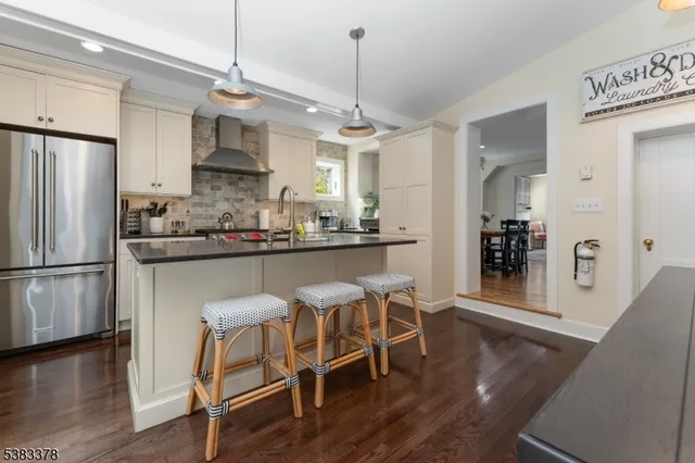 a kitchen with stainless steel appliances granite countertop a dining table chairs refrigerator and sink