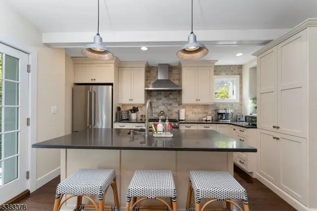 a kitchen with stainless steel appliances granite countertop a stove refrigerator a dining table and chairs with wooden floor