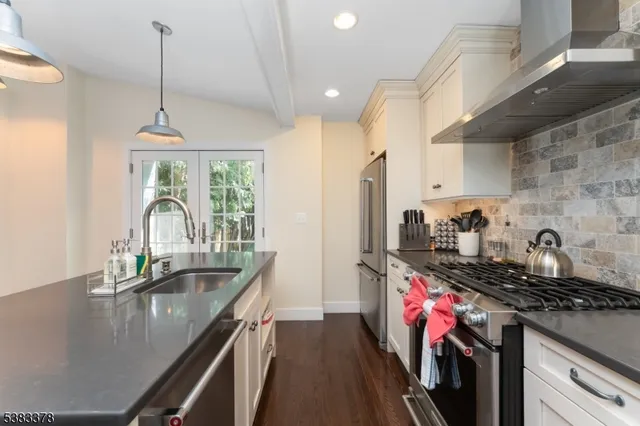 a kitchen with stainless steel appliances granite countertop a sink a stove and a wooden floors