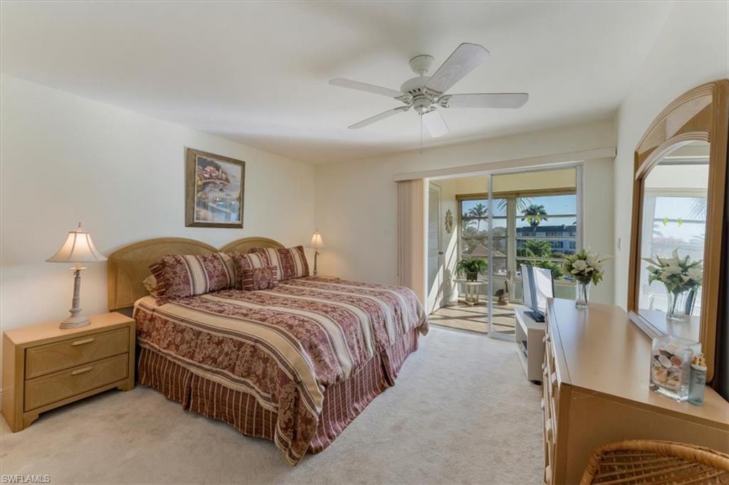 315 St Andrews Boulevard, Unit B32 Naples, FL 34113 - Photo 18 of 27 a spacious bedroom with a bed and large mirror