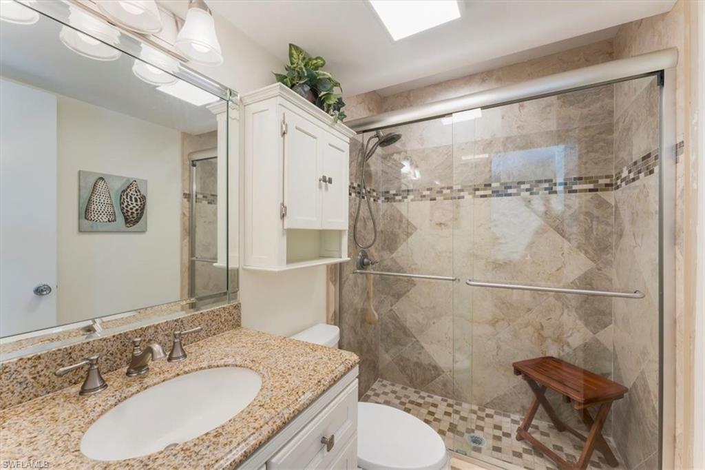 315 St Andrews Boulevard, Unit B32 Naples, FL 34113 - Photo 23 of 27 a bathroom with a granite countertop sink toilet a mirror and shower