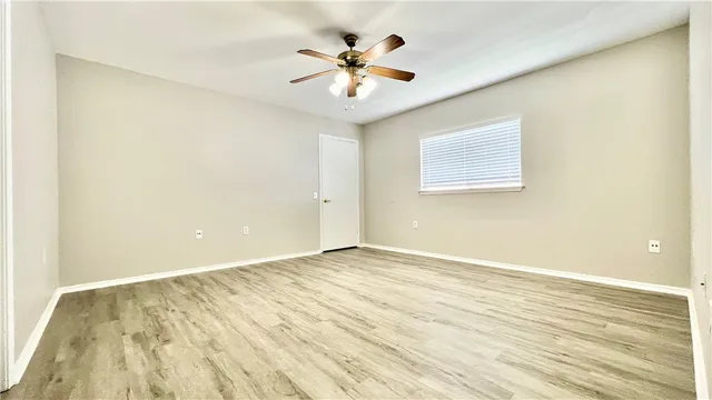 an empty room with wooden floor and ceiling fan
