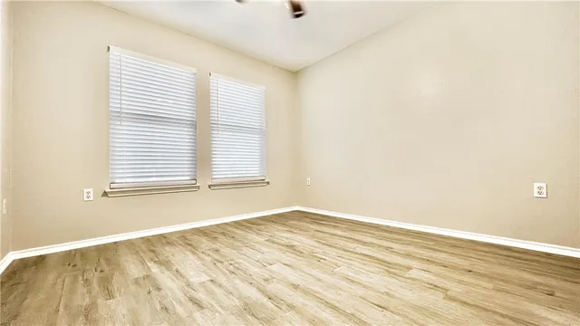 an empty room with wooden floor and windows