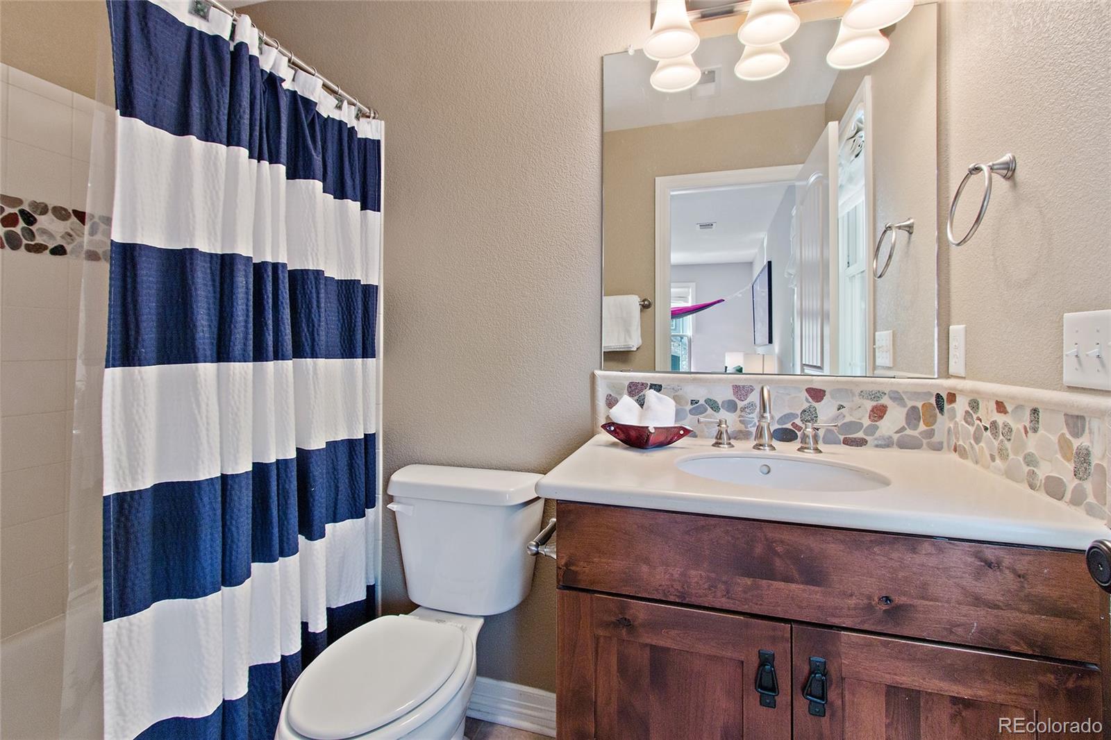 791 Elk Rest Road Evergreen, CO 80439 - Photo 23 of 35 a bathroom with a sink a toilet a mirror and shower curtain