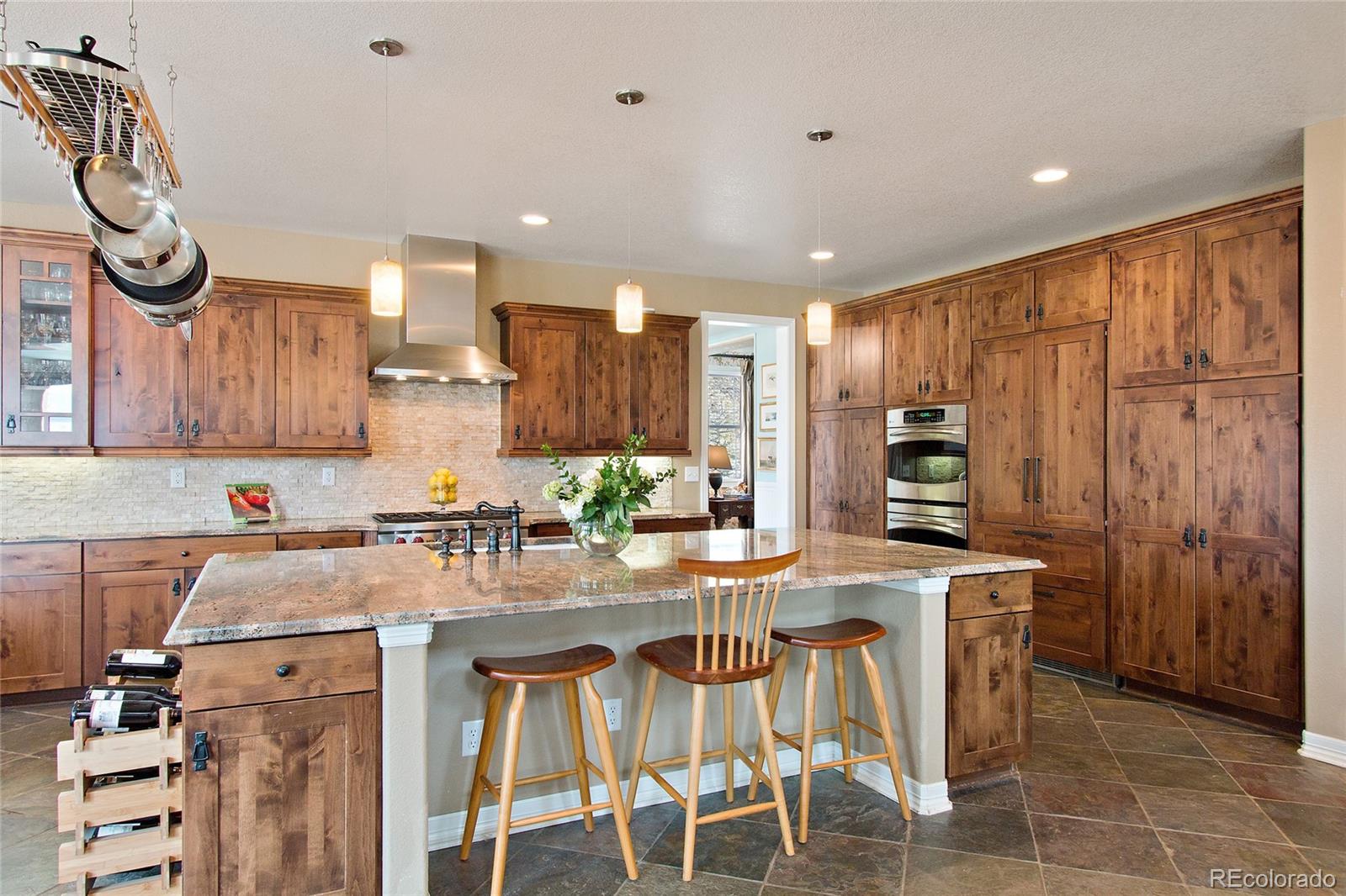 791 Elk Rest Road Evergreen, CO 80439 - Photo 10 of 35 a kitchen with stainless steel appliances granite countertop a sink a stove a refrigerator cabinets and chairs