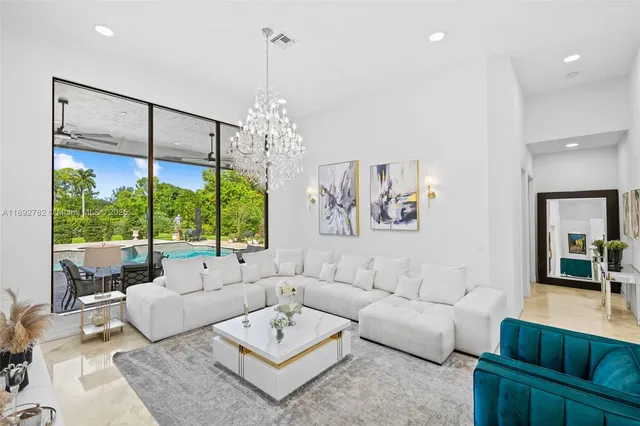 a living room with furniture a large window and a chandelier