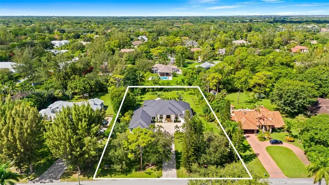 an aerial view of residential houses with outdoor space and trees