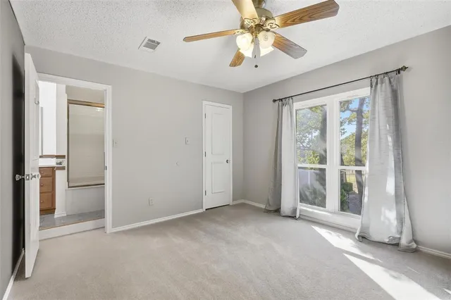 an empty room with chandelier fan and windows