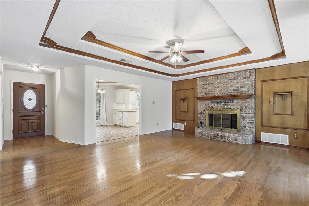 6140 Dick Price Road Fort Worth, TX 76140 - Photo 9 of 40 a view of a livingroom with a fireplace a ceiling fan and wooden floor