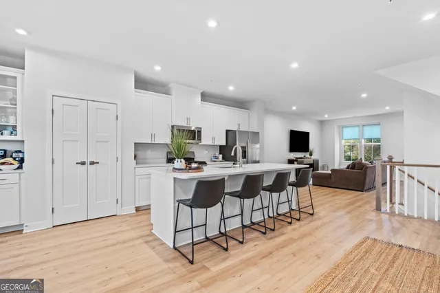 a kitchen with stainless steel appliances kitchen island granite countertop a table chairs sink and cabinets