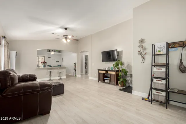 a living room with furniture a flat screen tv and a refrigerator