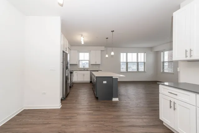 a kitchen with stainless steel appliances granite countertop a stove a sink and white cabinets with wooden floor