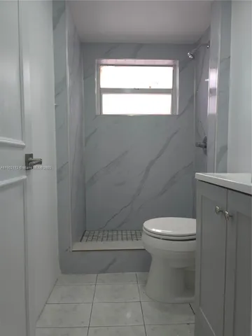a view of an empty room with wooden floor and window