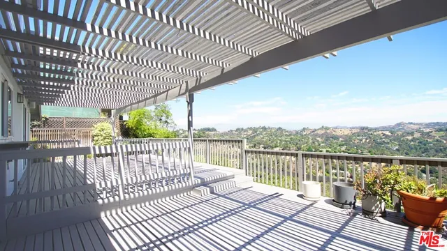 a balcony with wooden floor next to a yard