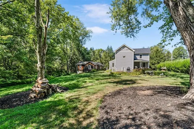 a view of a house with a yard and large trees