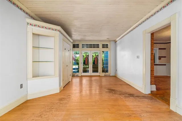a view of an empty room with window and wooden floor
