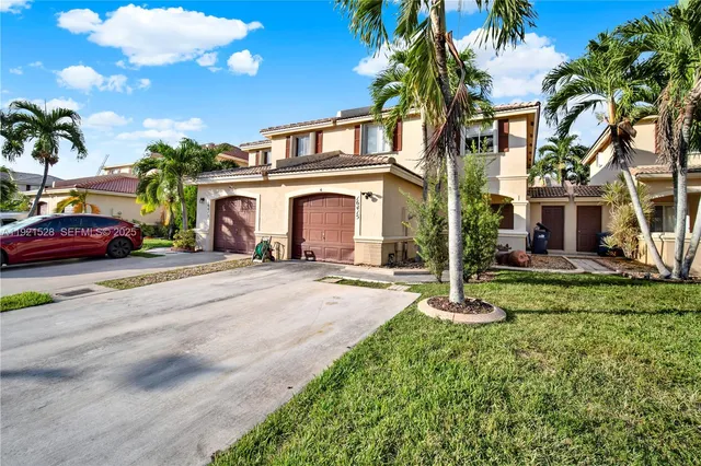 a front view of a house with a yard and palm trees