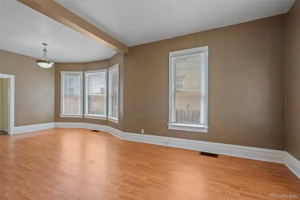 a view of an empty room with window and wooden floor