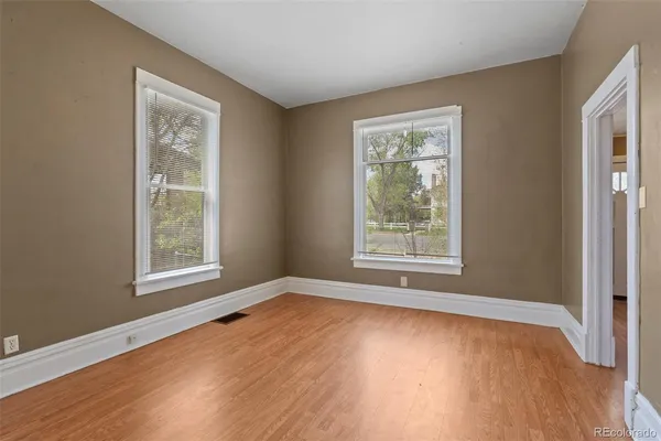 a view of an empty room with wooden floor and a window