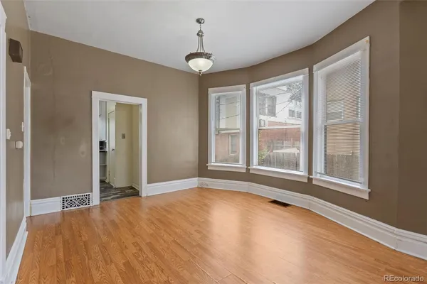 a view of an empty room with a window and wooden floor