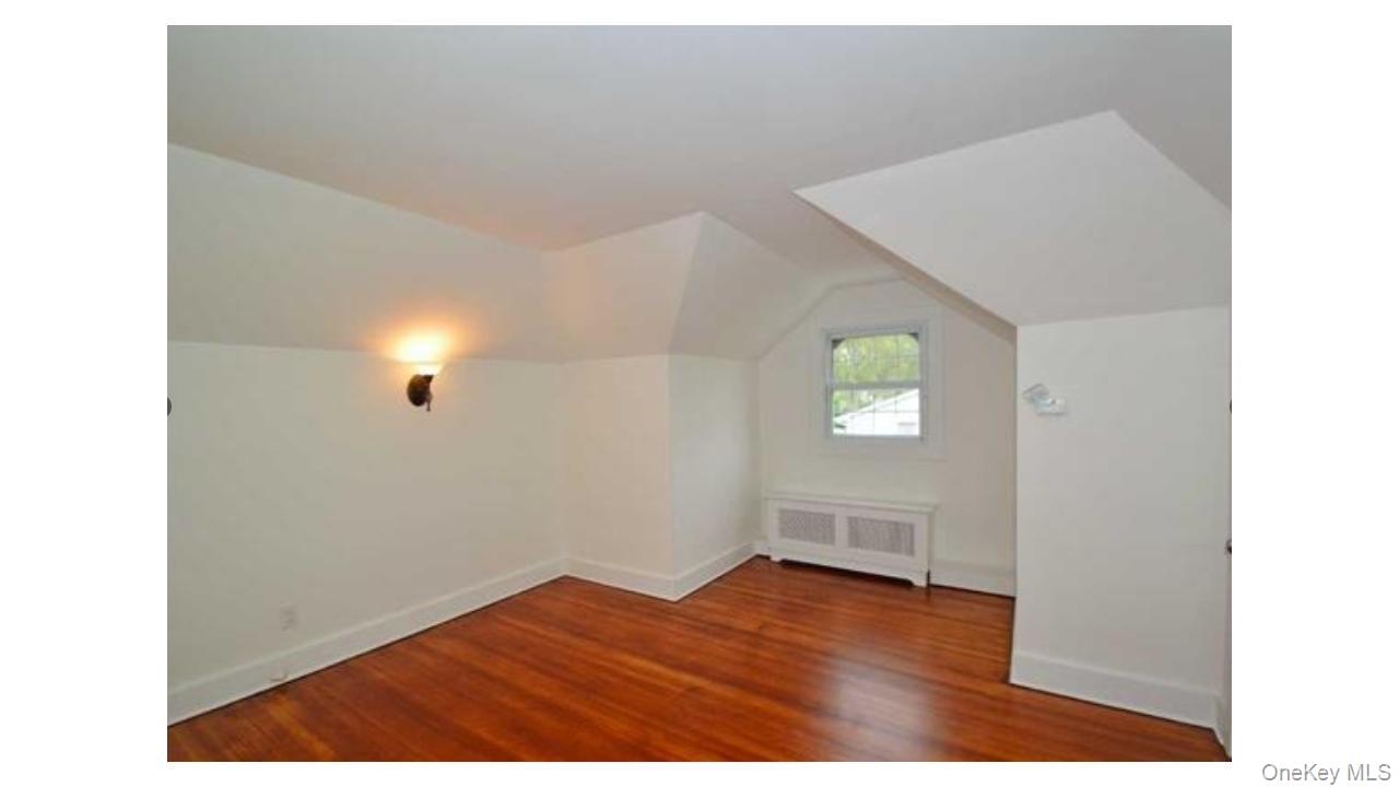 2 Arleigh Road Great Neck, NY 11021 - Photo 18 of 22 Hardwood flooring, painted white trim, window, wall-mounted sconce, and radiator cover