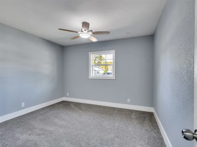 an empty room with a window and a fan