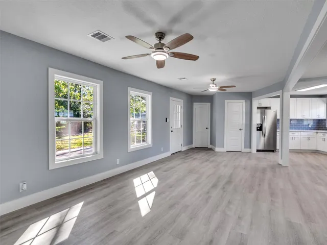 a view of empty room with wooden floor and fan