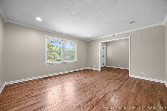 an empty room with wooden floor and window