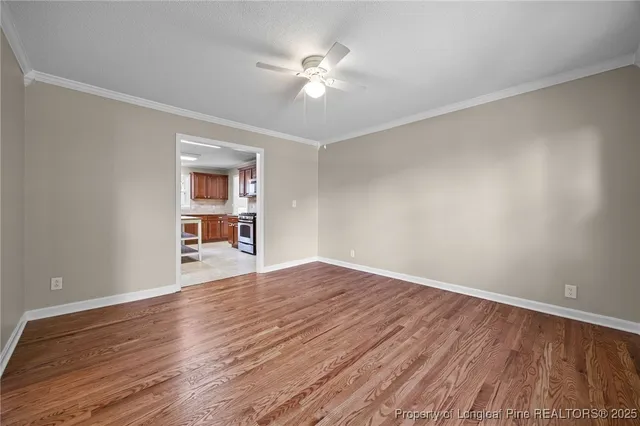 a view of an empty room with a window and wooden floor