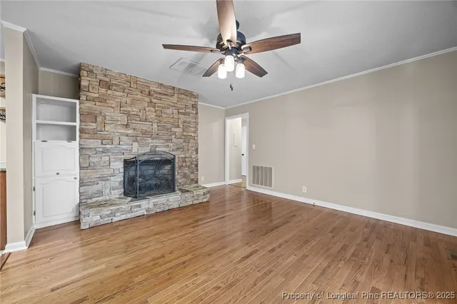 an empty room with wooden floor a fireplace a ceiling fan and wooden floor