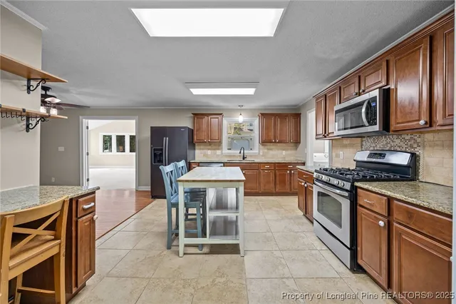 a kitchen with stainless steel appliances granite countertop a stove top oven a sink a dining table and chairs