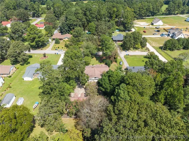 an aerial view of a residential houses with outdoor space and trees all around