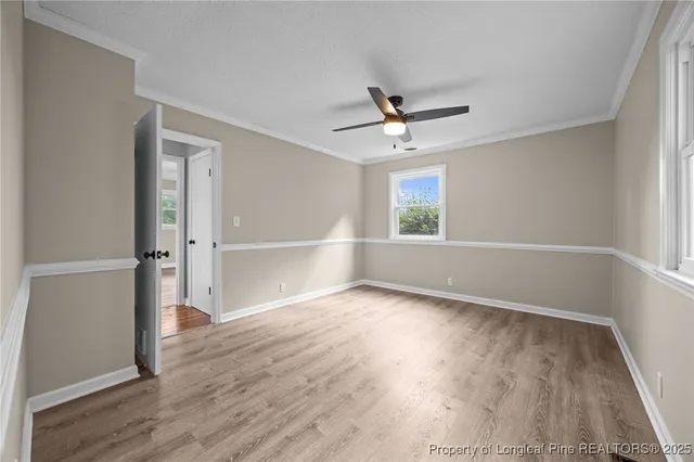 an empty room with wooden floor fan and windows