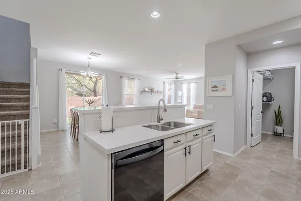 a kitchen that has a lot of white cabinets and stainless steel appliances