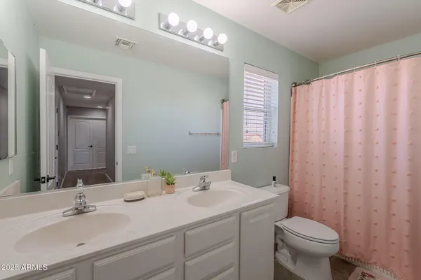 a bathroom with a double vanity sink toilet and a mirror