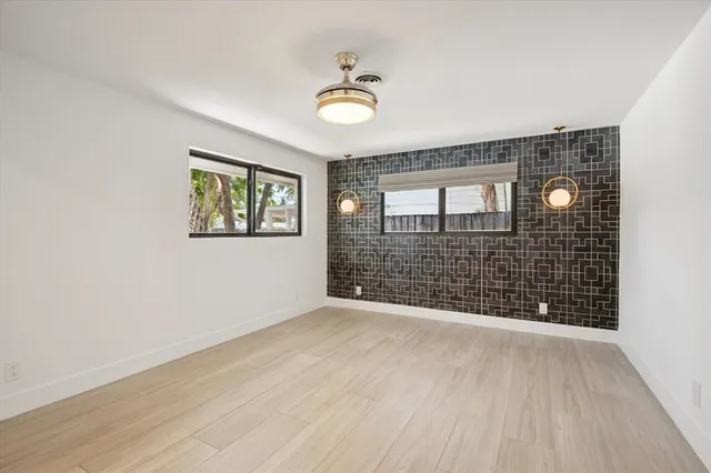 a view of an empty room with a window and wooden floor