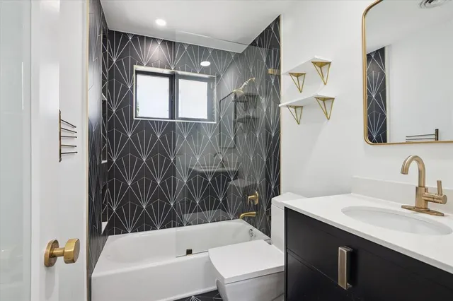a bathroom with a bathtub shower sink vanity and toilet