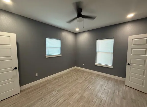 a view of an empty room with a window and wooden floor