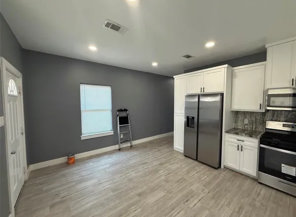 a view of kitchen with stainless steel appliances granite countertop a refrigerator and a stove top oven
