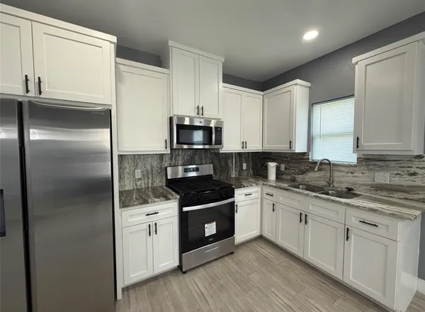 a kitchen with a sink white cabinets and stainless steel appliances