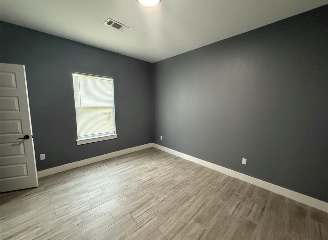 9815 Garcroft Street Houston, TX 77029 - Photo 7 of 14 an empty room with wooden floor and windows