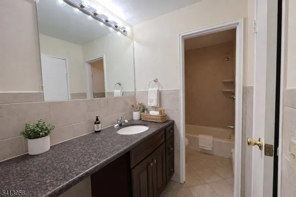 a bathroom with a granite countertop sink a mirror and a potted plant