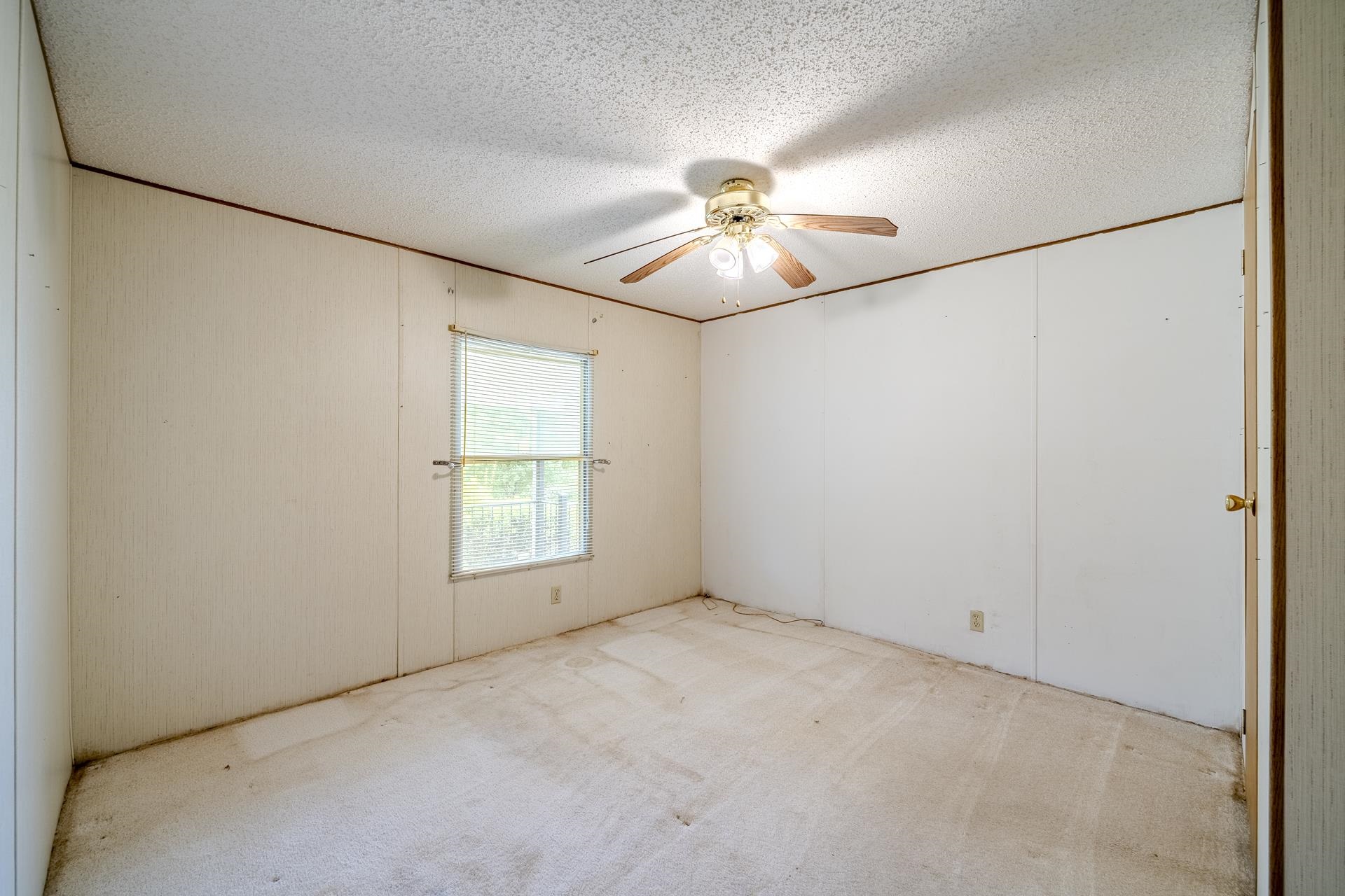 859 Old Morris Chapel Road Adamsville, TN 38310 - Photo 33 of 39 Room featuring a single window, a ceiling fan with light fixture, and textured paneling on the walls