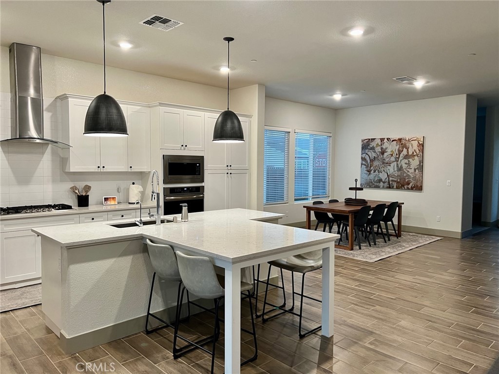 3751 Gabriel Drive Merced, CA 95340 - Photo 14 of 30 a kitchen with stainless steel appliances kitchen island granite countertop a stove a sink a dining table and chairs with wooden floor